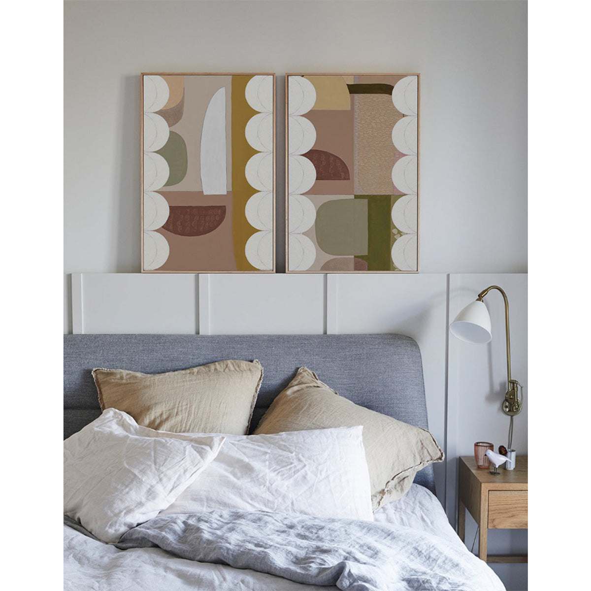 Two framed artworks with a scallop motif hanging above a bed in a bedroom setting