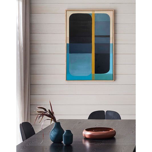 Abstract art piece on a wall above a dining table with decor items.